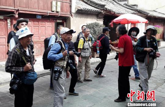 云南省摄影家协会副主席徐晋燕(红衣)在云南巍山古城向两岸摄影家介绍古城渊源。　周志鸿 摄