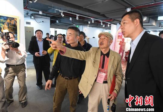 85岁高龄的台湾著名摄影家许捷芳(右二)向来宾介绍自己参展摄影作品的创作经过。　记者刘可耕 摄