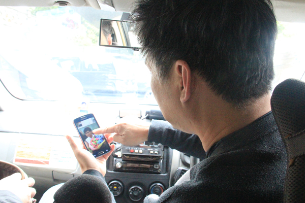 出租车司机老梁向记者展示自己家人的照片。